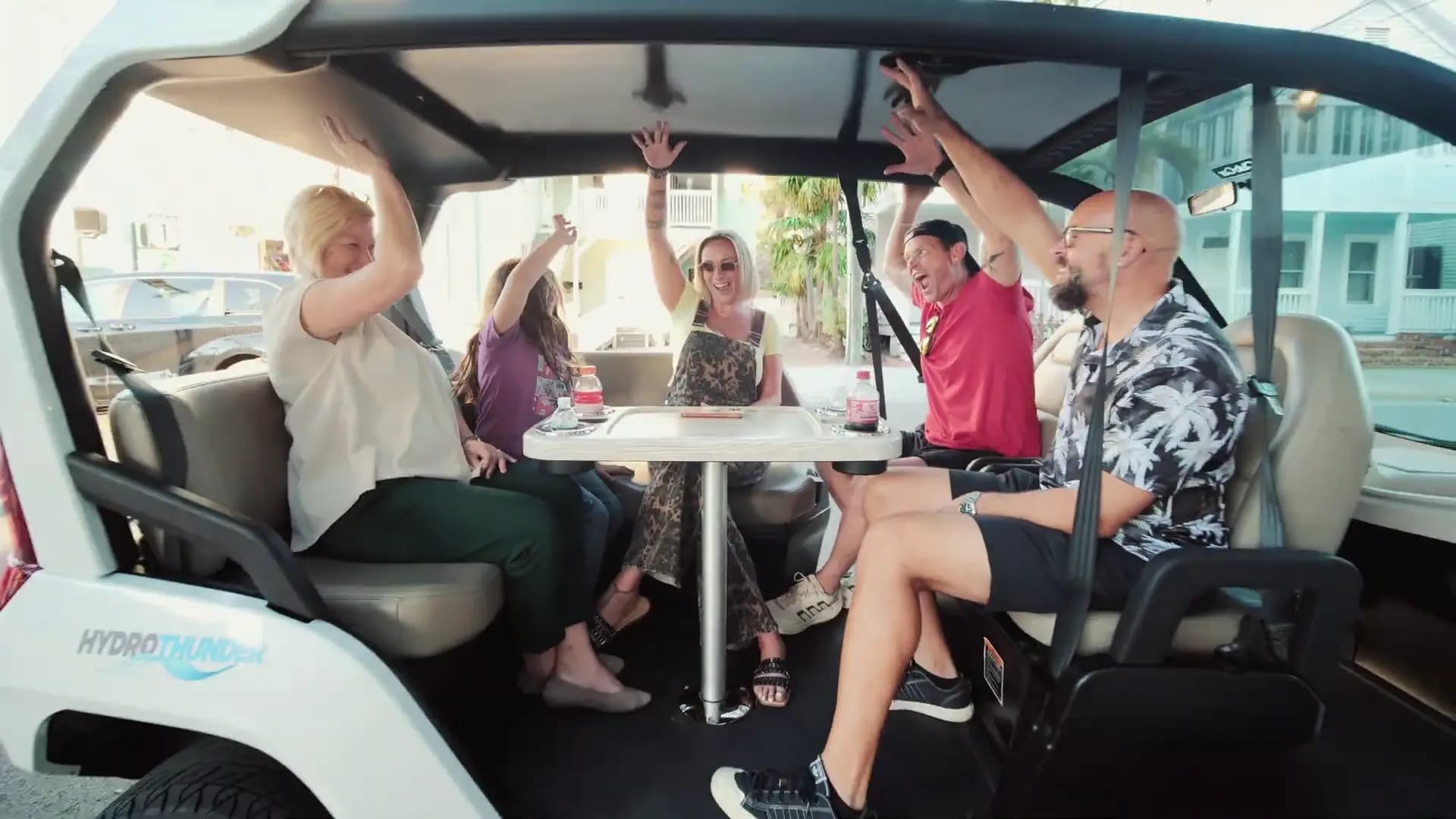 Happy riders with hands up in a HydroThunder electric car