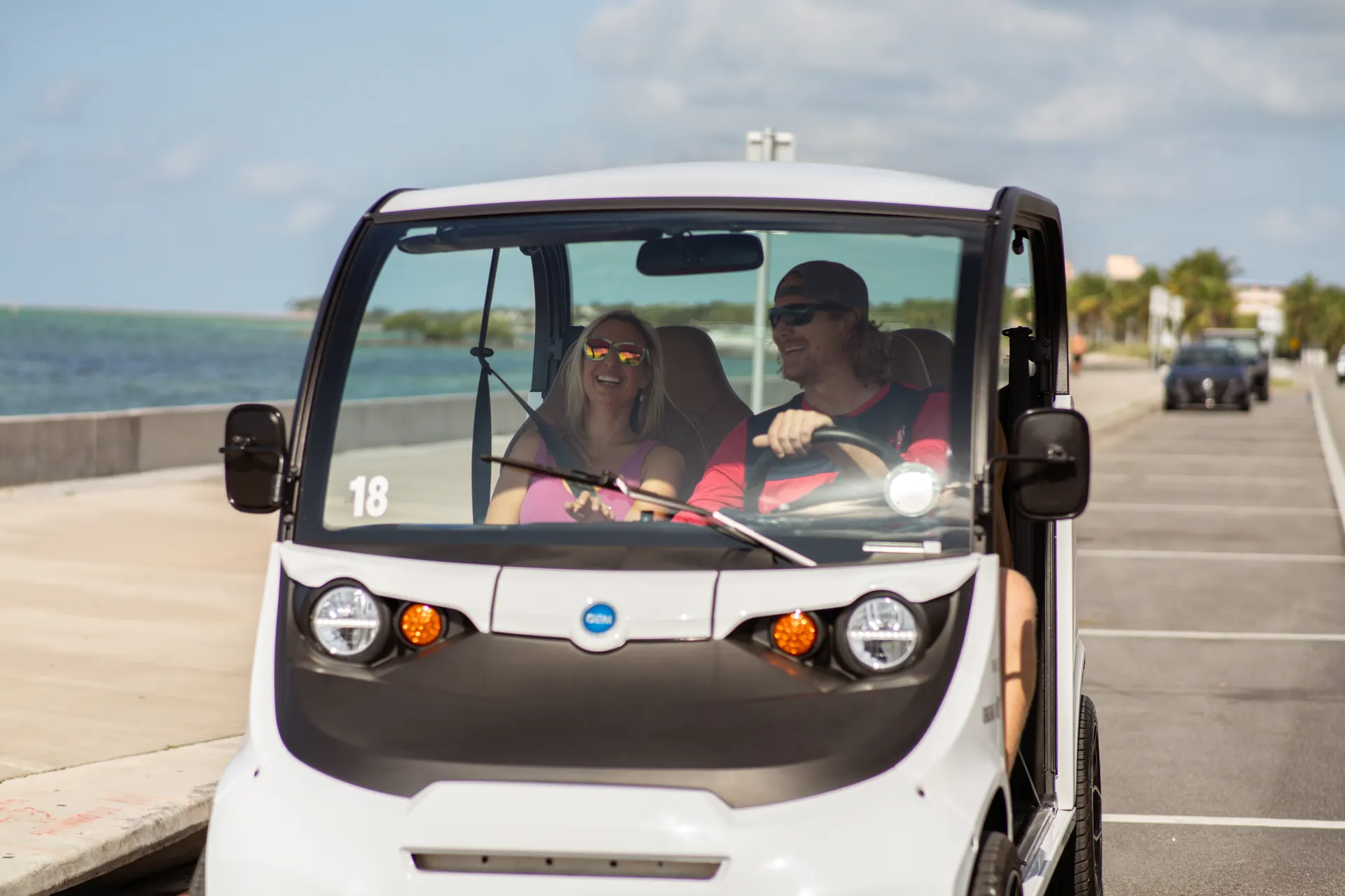 Couple driving a GEM electric car along the Key West waterfront